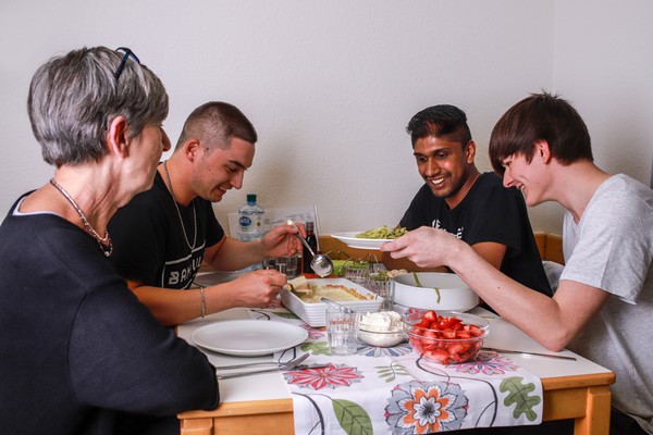 Eine Gruppe von Teilnehmern isst gemeinsam mit ihrer Betreuerin