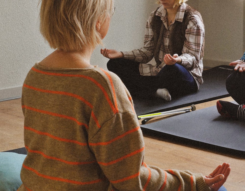 Personen im Schneidersitz auf Yogamatten