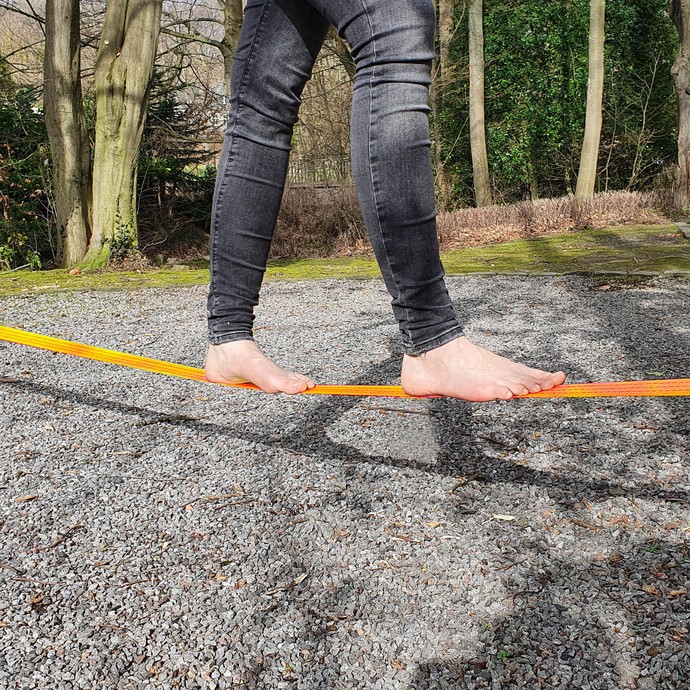 Eine Person balanciert barfuß über eine Slackline