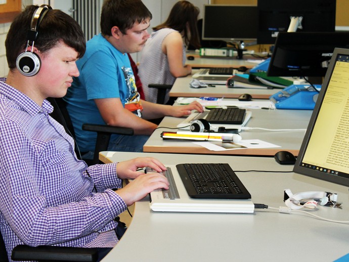 Teilnehmerinnen und Teilnehmer arbeiten mit der Braillezeile an Computern (vergrößerte Bildansicht wird geöffnet)