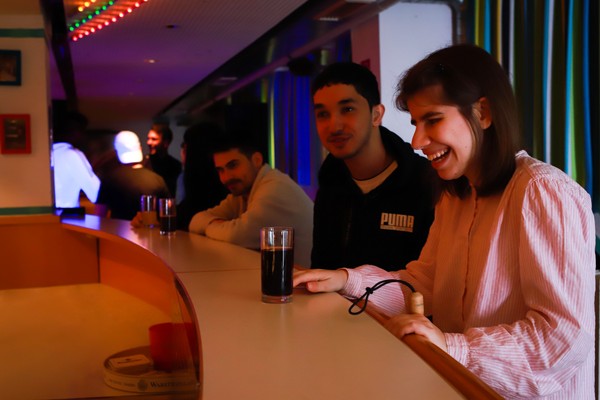 Teilnehmerinnen und Teilnehmer bei einem Glas Cola in der Diskothek