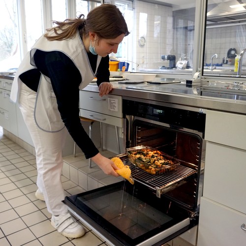 Teilnehmerin nimmt einen Auslauf aus dem Backofen