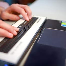 Händen tippen auf einer Braillezeile am Laptop