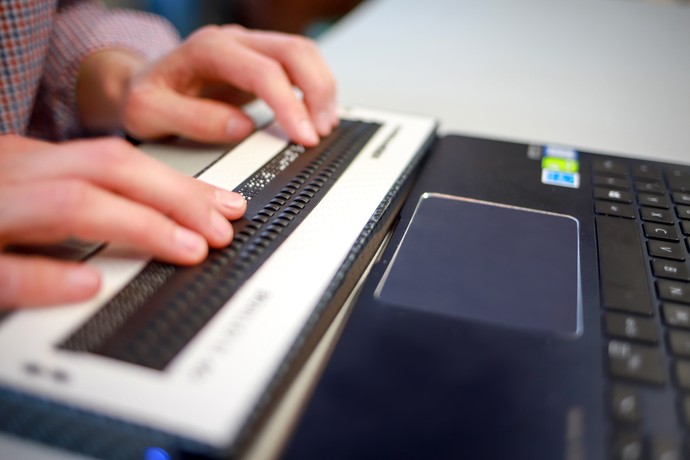 Hände bedienen eine Brailletastatur