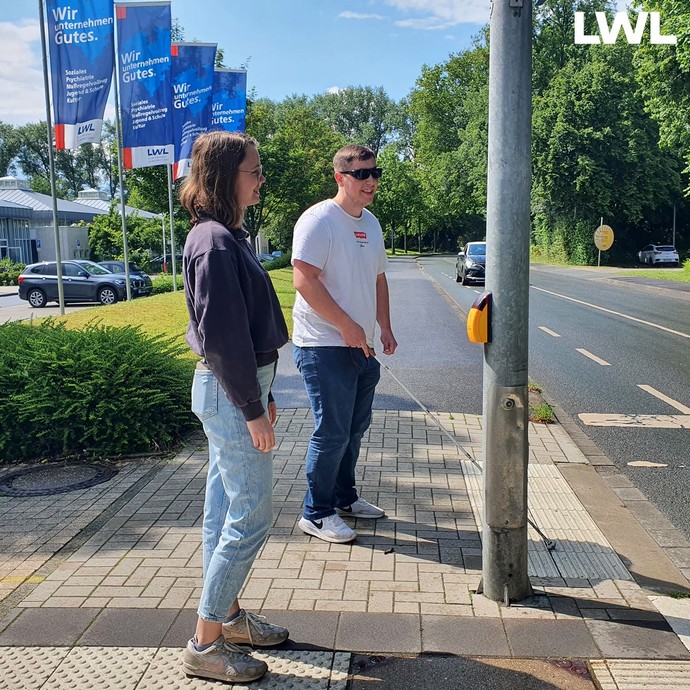 FSJlerin Lena Teipel steht mit einem Teilnehmer an der Ampel vor dem BBW-Gelände.