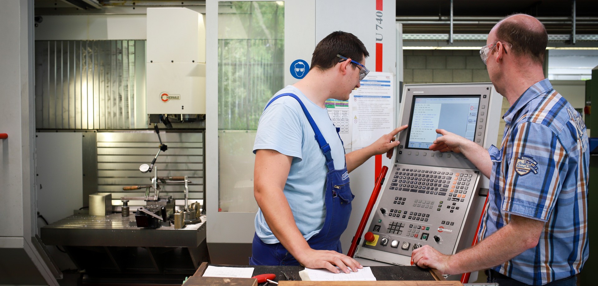 Ein Auszubildender der Metalltechnik mit seinem Ausbilder an einer Maschine