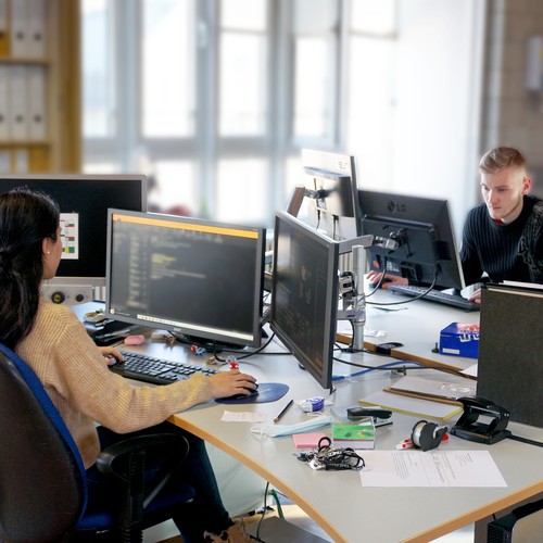 Teilnehmerin und Teilnehmer sitzen an ihren PC-Arbeitsplätzen